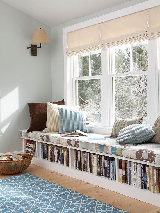 a cozy upholstered windowsill with pillows and books inside the bench