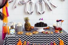 10 a cheerful beach-inspired dessert table with silver letter balloons and a colorful tassel garland