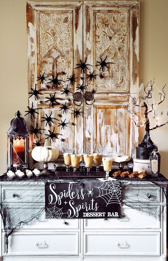 a stylish dessert table with black spiders, candle lanterns and a sign can be easily recreated