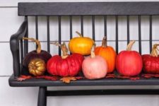 13 colorful fall pumpkins displayed on a bench of your porch is a chic and bold idea