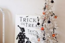14 a Halloween tree with orange and black ornaments, a black and white sign and some figurines