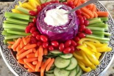 14 a veggie tray with dip placed into a cabbage for a cute and cozy rustic look