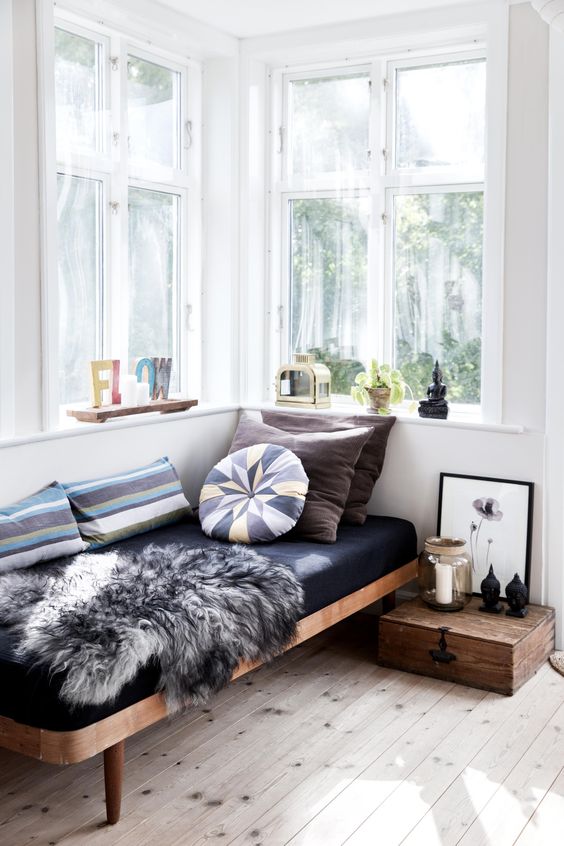 a daybed by the window with pillows and a throw blanket for reading