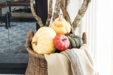 02 a tall basket with various pumpkins, large branches and a blanket by the fireplace