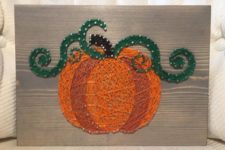 05 a creative pumpkin string art piece with two shades of orange and green leaves