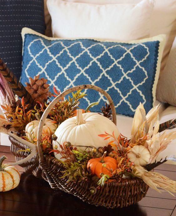 a basket with pumpkins, feathers, pinecones, faux greenery and corn husks