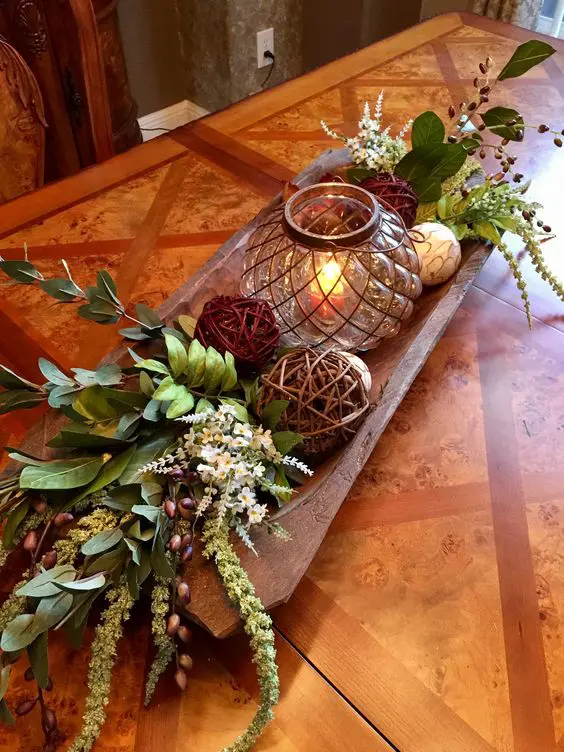 a bread bowl with wicker balls, acorns, greenery and white blooms as a centerpiece