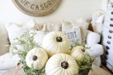 a metal basket with white pumpkins and fresh greenery for a neutral look