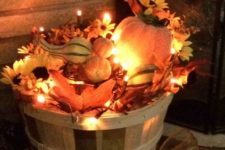 14 a wooden basket with faux leaves, pumpkins, faux blooms and lots of lights