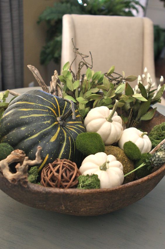 a large bowl with white and green pumpkins, moss balls, foliage and driftwood