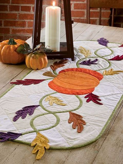 an embroidered and applique pumpkin and leaf table runner for Thanksgiving