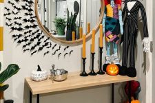 Nightmare Before Christmas entryway decor with a mirror and bats around it, themed dollls, candles, jack-o-lanterns