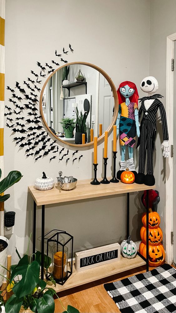 Nightmare Before Christmas entryway decor with a mirror and bats around it, themed dollls, candles, jack o lanterns