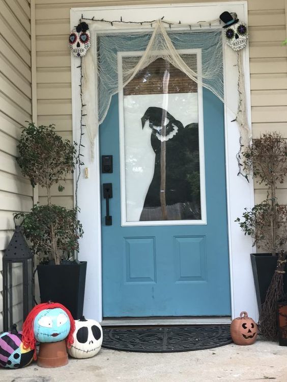 a Nightmare Before Christmas porch with painted pumpkins, door decor, cheesecloth and some sugar skulls