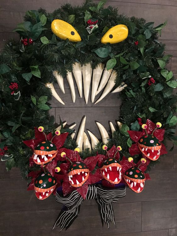 a Nightmare Before Christmas wreath with monsters and a ribbon bow, with leaves and berries is a cool Halloween decoration