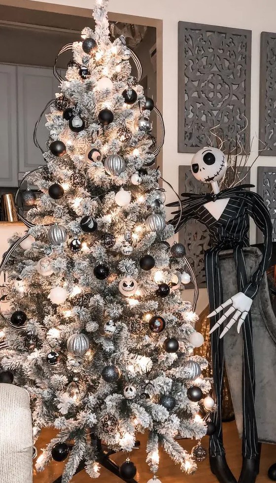 a beautiful grey Christmas tree with white, black and silver ornaments, Jack Skellington ones and his figure next to the tree