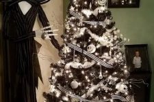 a black Christmas tree with black and white ribbons, white garlands, lights and black and white Skellington ornaments plus Jack Skellington next to it
