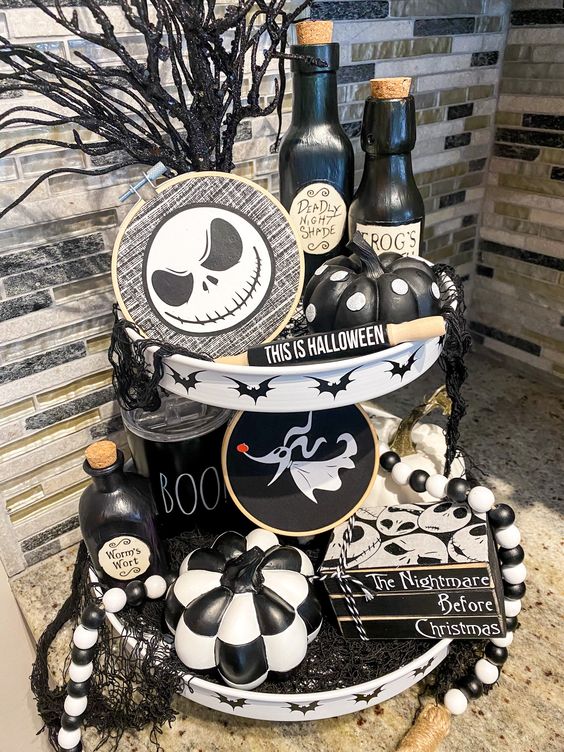a black and white Nightmare Before Christmas shelf styled with pumpkins, embrodiery hoop decor, black branches and bottles