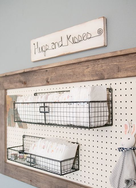 a framed pegboard with metal crate shelves over the changing table is a great idea