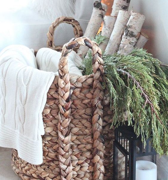 a basket with cable knit blankets, evergreens and tree branches for a natural feel