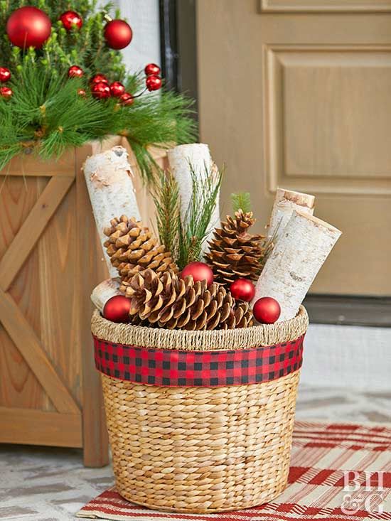 a basket with large pinecones, Christmas ornaments and birch logs for a holiday feel