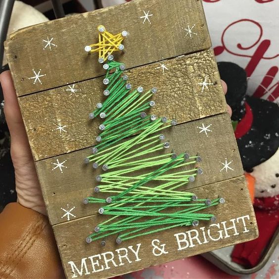 a reclaimed wood sign with a gree Christmas tree string art