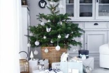 14 a small tree in a basket with various white ornaments and lights
