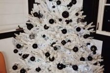 a crispy white Christmas tree with black matte and glossy ornaments and lights is a cool and fresh idea for a modern space