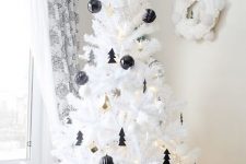 a lovely white Christmas tree decorated with black baubles and little Christmas trees, with gold bells and lights is amazing