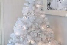 a pure white Christmas tree with lights and silver and white ornaments plus a star on top