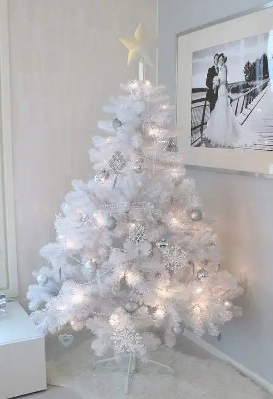 a pure white Christmas tree with lights and silver and white ornaments plus a star on top