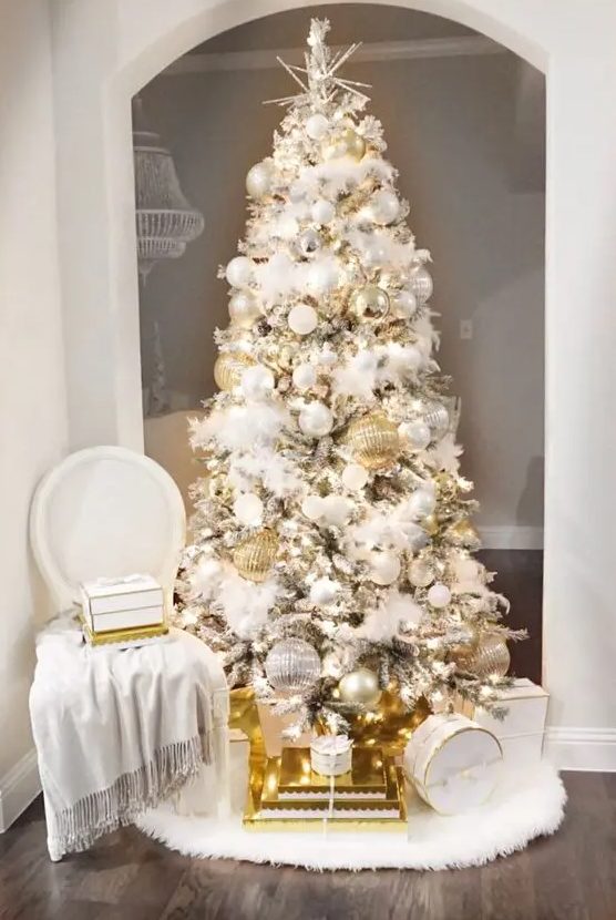 a refined and glam Christmas tree with white and silver plus oversized gold ornaments, lights and a star topper