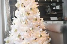 a small white Christmas tree with lights and gold and pearly ornaments placed into a basket is cool