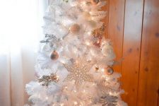 a white Christmas tree decorated with copper and white ornaments and lights is a chic and cool idea for a modern space