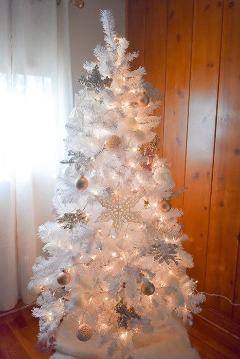 a white Christmas tree decorated with copper and white ornaments and lights is a chic and cool idea for a modern space