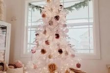 a white Christmas tree decorated with fluffy pompoms of earthy colors and put into a basket to make it look a bit rustic