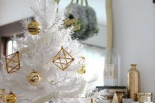 a white Christmas tree decorated with gold bauble and himmeli ornaments and a shiny gold star topper