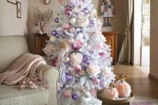 a white Christmas tree decorated with lilac, pink baubles and faux blooms looks very refined