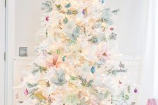 a white Christmas tree decorated with lots of various pastel ornaments, lights and an angel tree topper plus pastel gift boxes