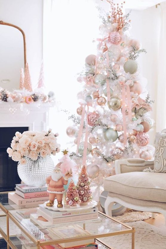 a white Christmas tree decorated with pastel pink, green and white ornaments, pink ribbon and pink branches on top