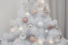 a white Christmas tree decorated with pink, white and silver ornaments and topped with a pink star