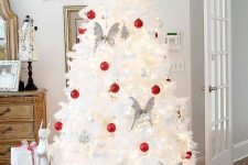 a white Christmas tree decorated with white and red ornaments and butterflies is a cool and catchy idea for a modern space