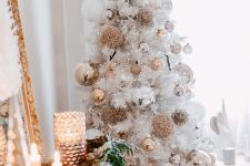 a white Christmas tree styled with silver and gold ornaments, usual and oversized ones
