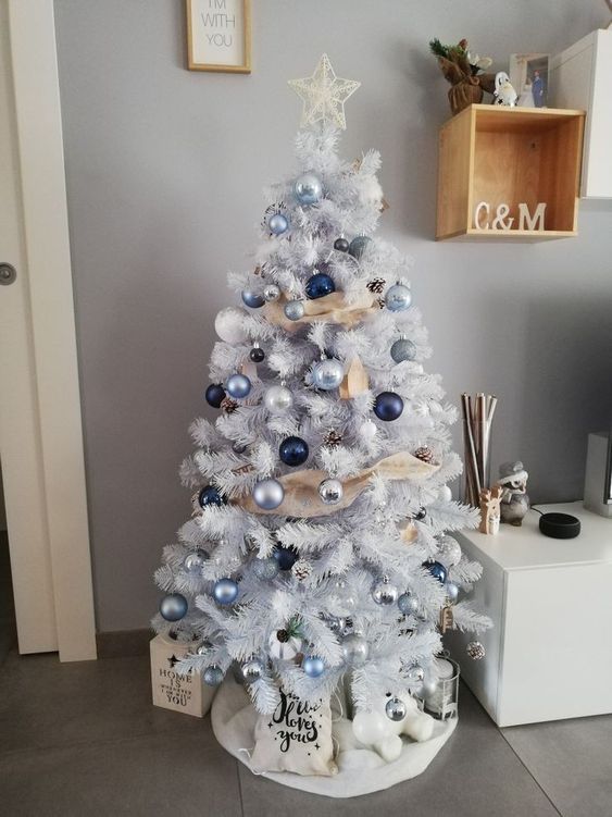 a white Christmas tree with blue, silver and navy ornaments and ribbons is a cool and catchy solution for a coastal space