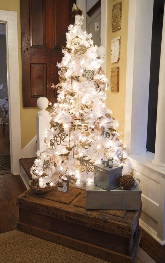 A white Christmas tree with lights decorated with vintage inspired ornaments and paper buntings is very cool