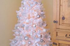 a white Christmas tree with lights, silver, white and shiny silver ornaments, a shiny star topper and some letters is wonderful