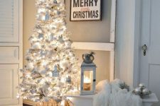 a white Christmas tree with lights, white ornamnets and houses is a cool and catchy solution