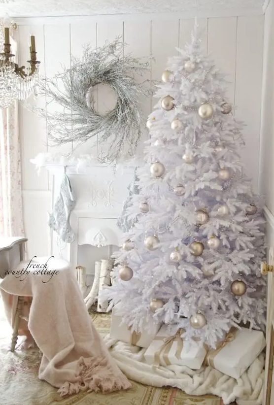 a white Christmas tree with pearly and greige ornaments and beads, a whitewashed twig wreath and white stockings on the mantel