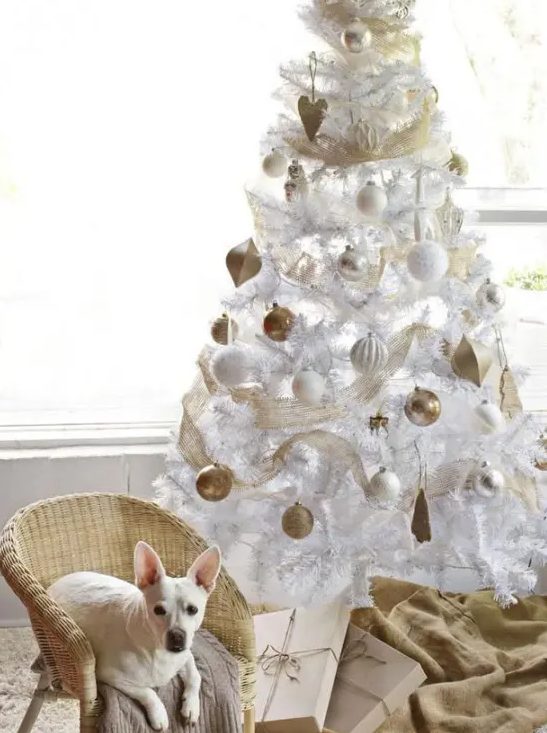 a white Christmas tree with white and gold ornaments, gold mesh ribbon is a chic and cool idea for a glam space