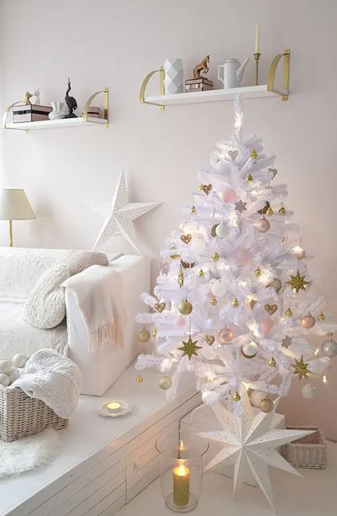 a white lit up Christmas tree with pink, gold and white ornaments, a large star is ideal for this glam white space